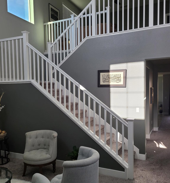 A professional interior paint with slate grey walls and stunning white stair railings